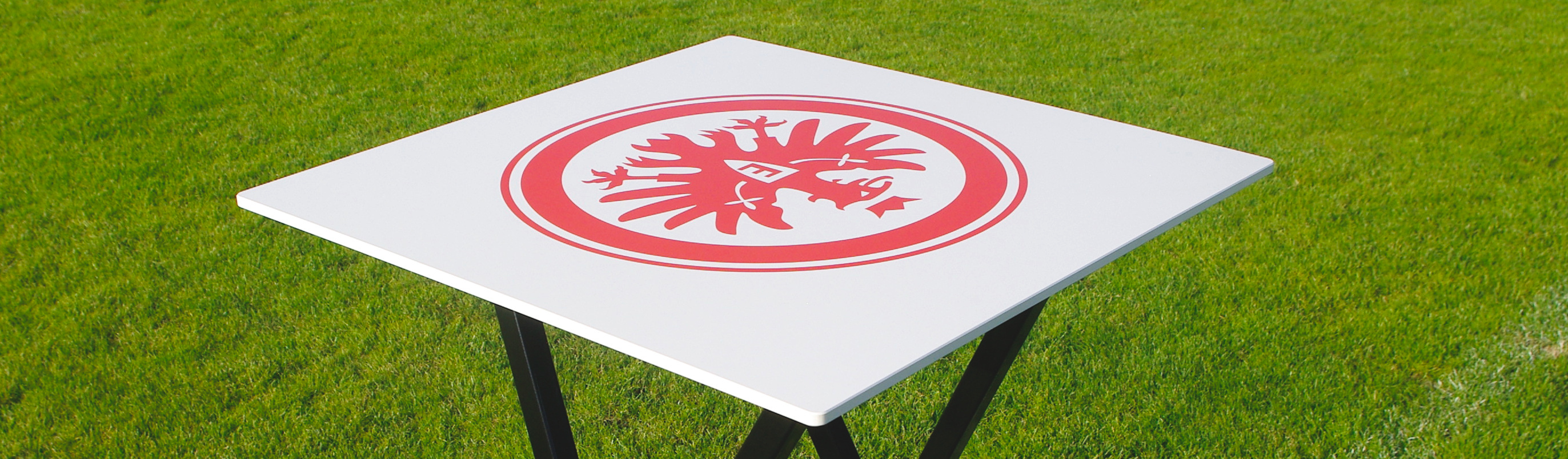 Stehtisch mit Eintracht Frankfurt Adler-Logo auf grüner Wiese