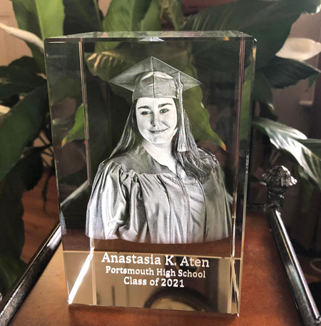 Crystal Print Graduation 3d Photo Crystal Block, engraved portrait of a smiling young woman in graduation cap and gown with engraved text showing her name and academic details.