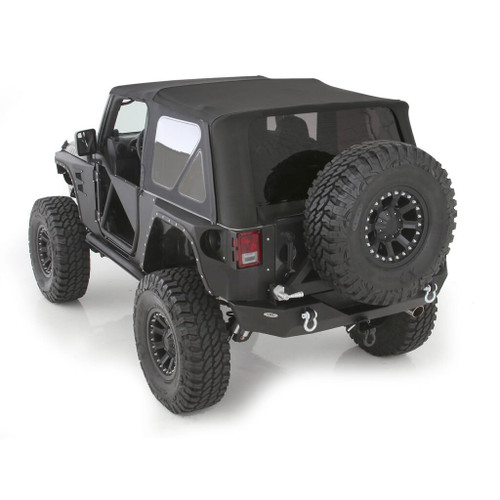 Black jeep showcasing large tires and a Smittybilt soft top with tinted windows, perfect for outdoor adventures.