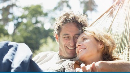 Couple holding hands and smiling in hammock