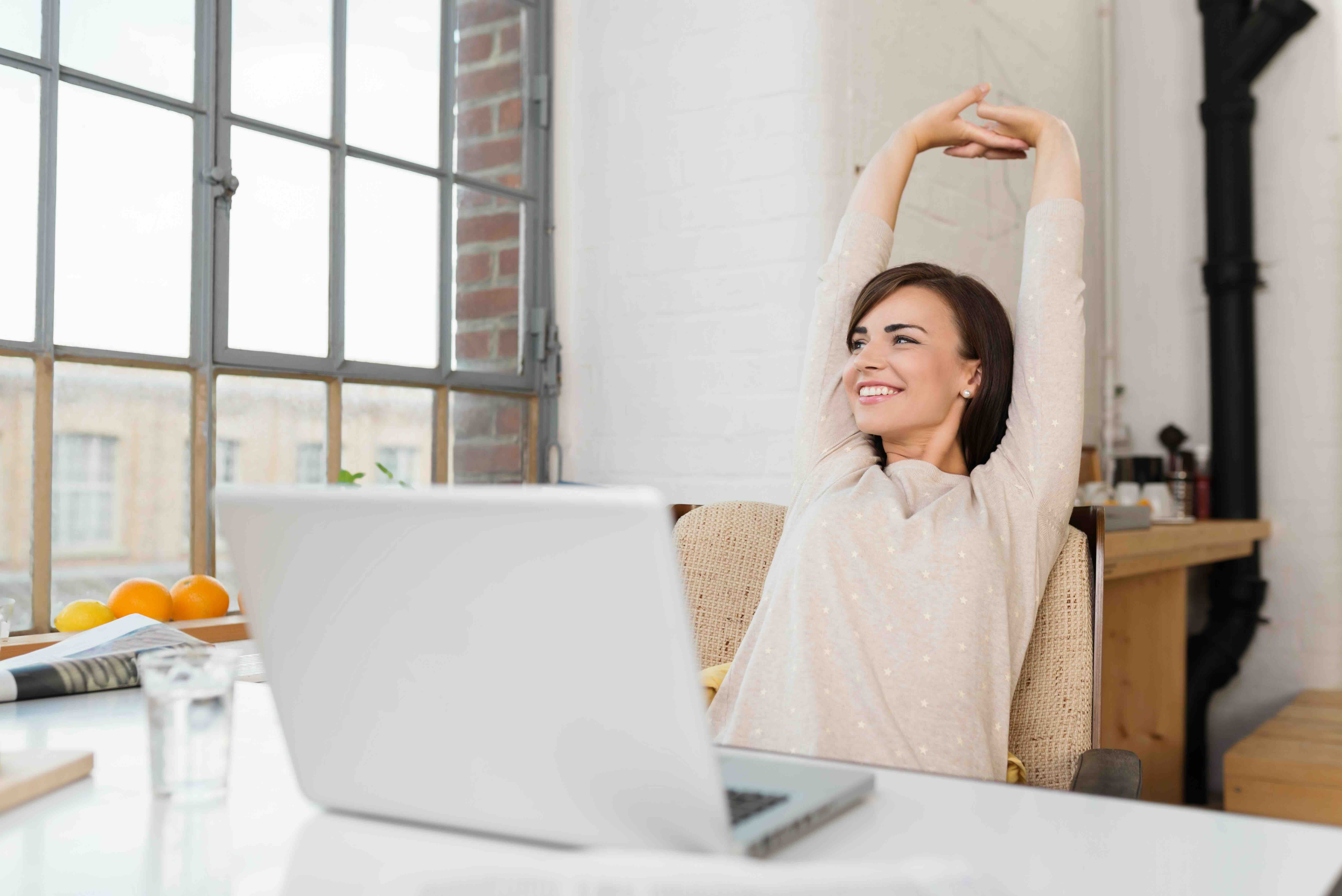 Woman stretching before open laptop
