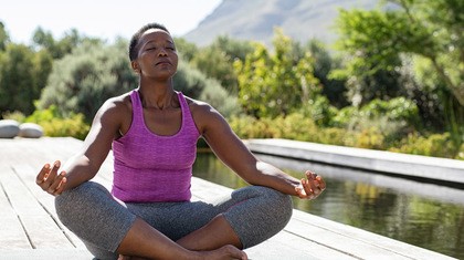 Woman meditating near water