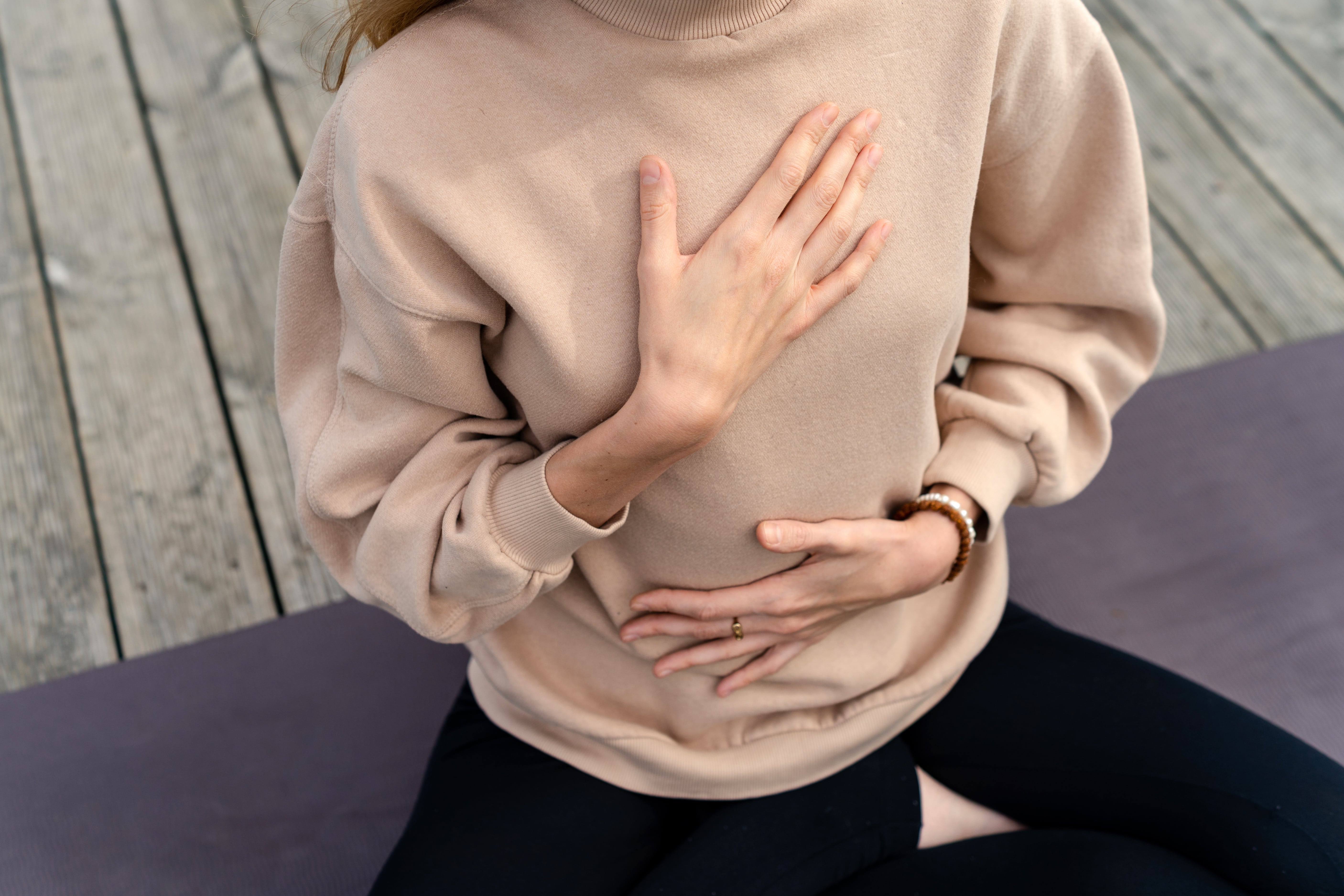 A woman places her hands on her chest and diaphragm to feel and guide how she is breathing.
