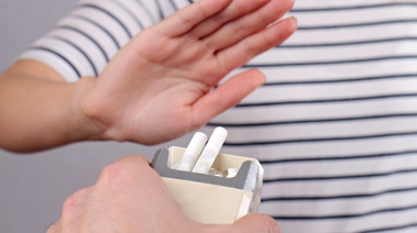A person offering cigarette to another person and another person is denying it.