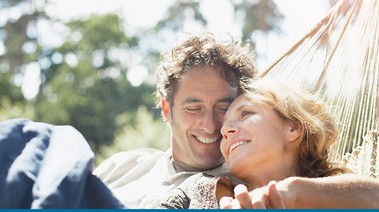 Couple holding hands and smiling in hammock
