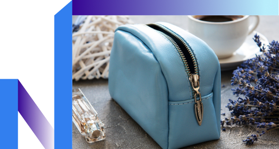 A blue leather purse with a flower next to a steaming cup of coffee on a wooden table.