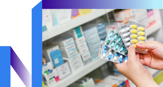 A person holds a pack of pills in a pharmacy.
