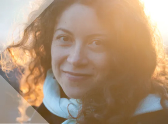 A smiling woman with curly hair in a scarf exudes happiness and charm.