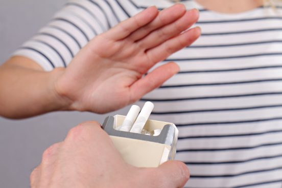 A person offering cigarette to another person and another person is denying it.