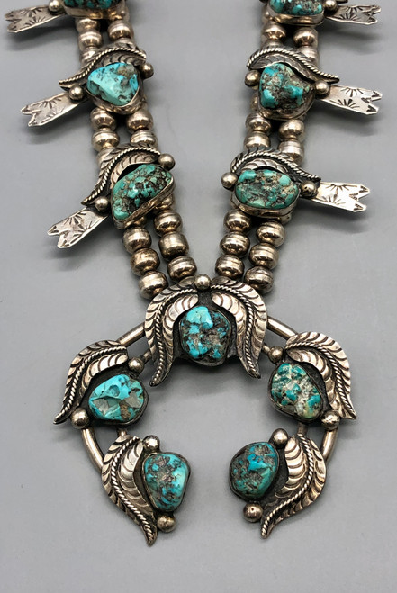 unique squash blossom necklace set with a matching ring, great turquoise nugget cabochons throughout the naja and blossoms, silver applique