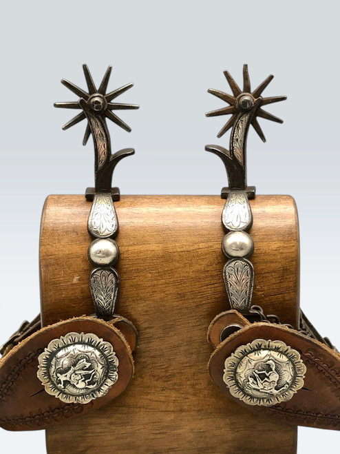 California style spurs, chap guards, inlaid silver, silver dot accents, concho style button, bucking horse figure, hell chains, leather straps, Circa late 1800s to early 1900s.