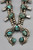 unique squash blossom necklace set with a matching ring, great turquoise nugget cabochons throughout the naja and blossoms, silver applique