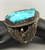 larger central turquoise stone, hand stamped designs, filework, twisted wire, silver dots, and silver applique