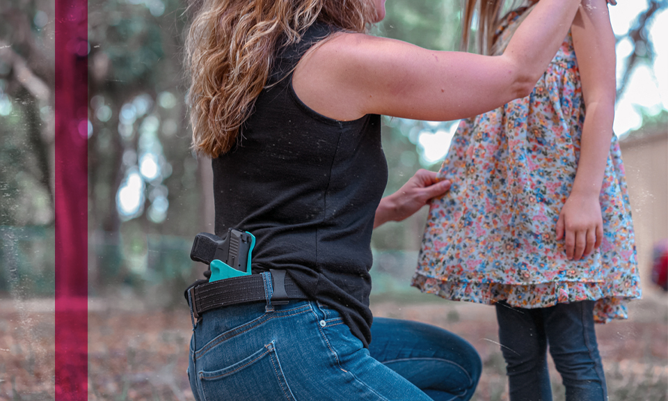 Mother, wearing a holstered weapon in a Tiffany Blue ProTuck holster, knealing down to speak with her daughter.