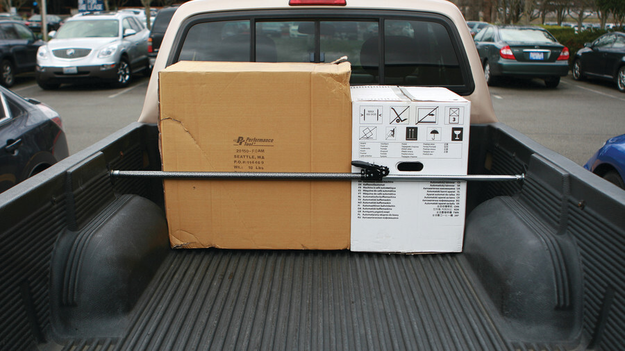 Performance Tool Cargo Accessories, featuring a cargo bar securing boxes in the back of a truck.