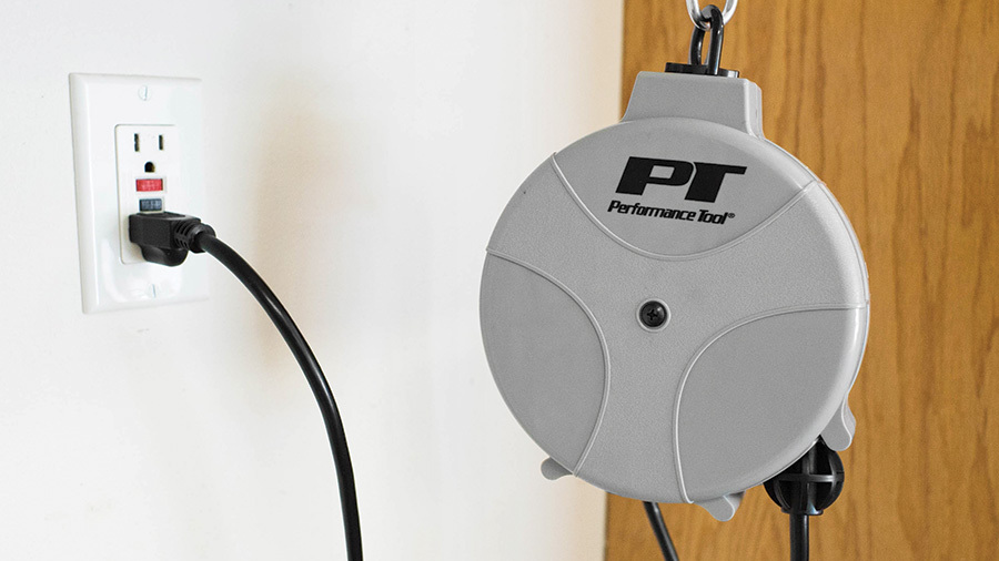 Performance Tool power tool cords and reels featuring a cord reel hanging from a hook and plugged into a wall