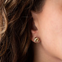 14K Yellow Gold Interlocking Love Knot Textured Stud Earrings on female model