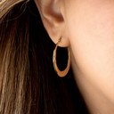 14K Yellow Gold Reversible Twist Hoop Earrings on female model