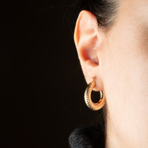 14K Yellow Gold Reversible Cut Textured Tube Huggie Hoop Earrings on female model