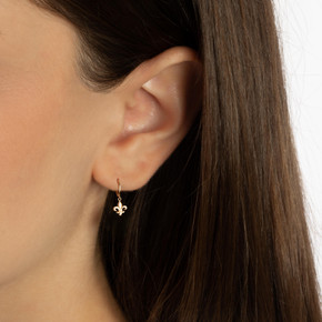 Yellow Gold French Fleur-de-Lis Drop Huggie Hoop Earrings on female model Yellow Gold French Fleur-de-Lis Drop Huggie Hoop Earrings on female model