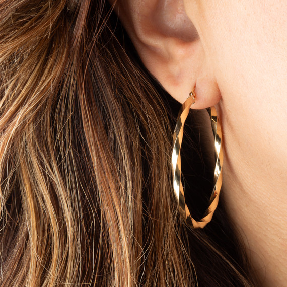 14K Yellow Gold Reversible Twist Tube Hoop Earrings on female model