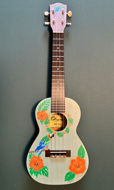 Hand‑painted Ohana CK Kit concert ukulele titled “Calypso,” featuring a macaw, orange hibiscus flowers, and tropical leaves on a vintage aqua stained wood body with professional setup.