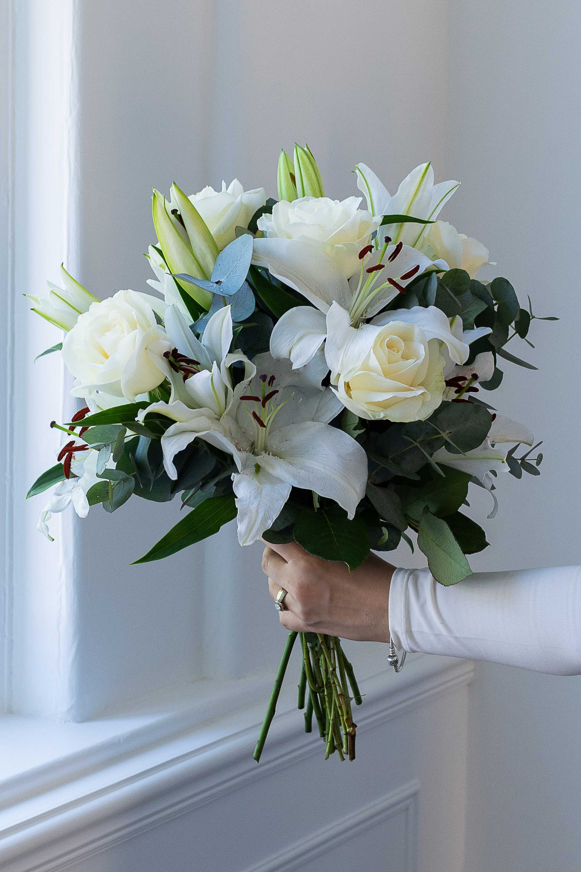 White lily and rose bouquet with eucalyptus foliage.