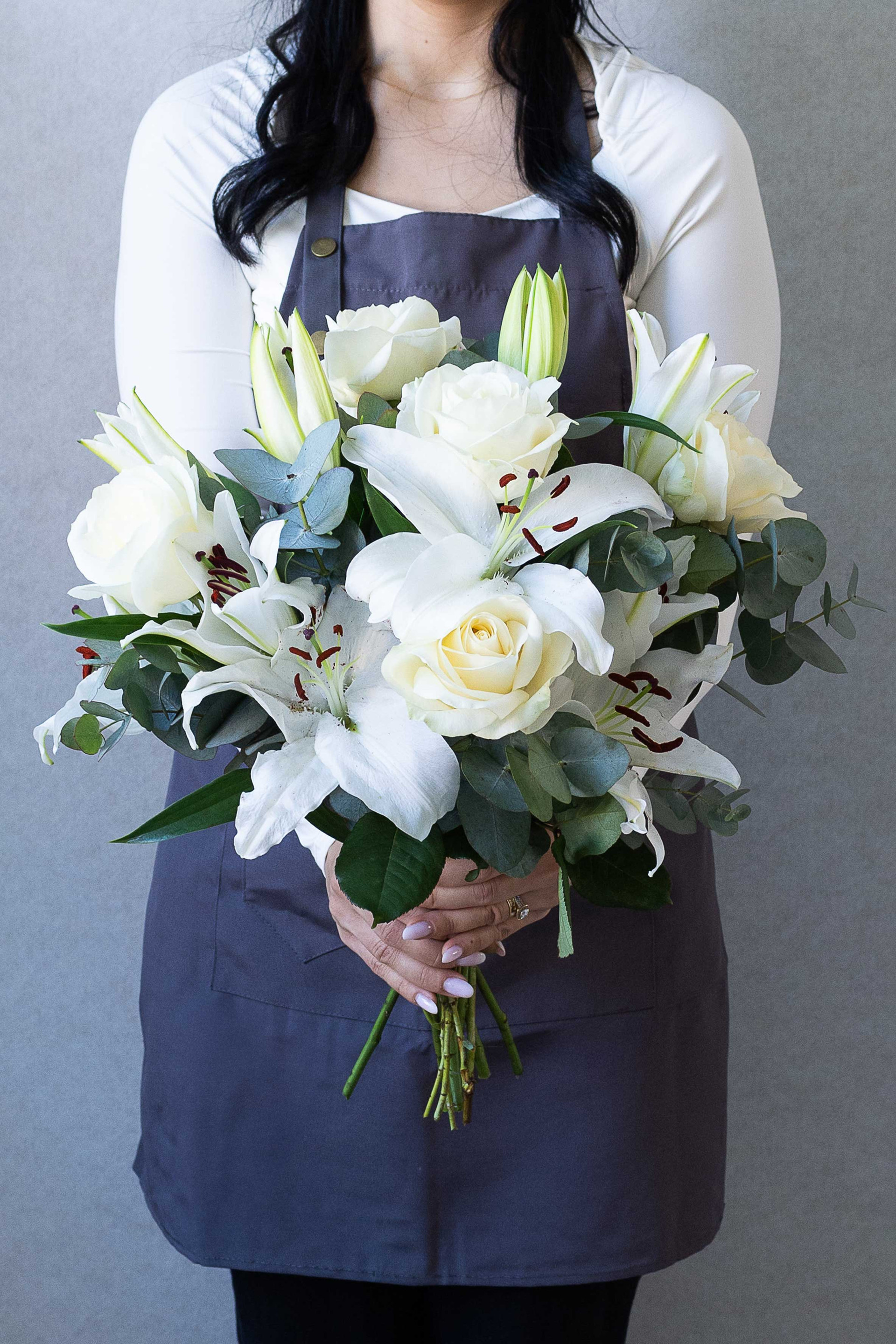 Florist holding an elegant white lily and rose bouquet.
