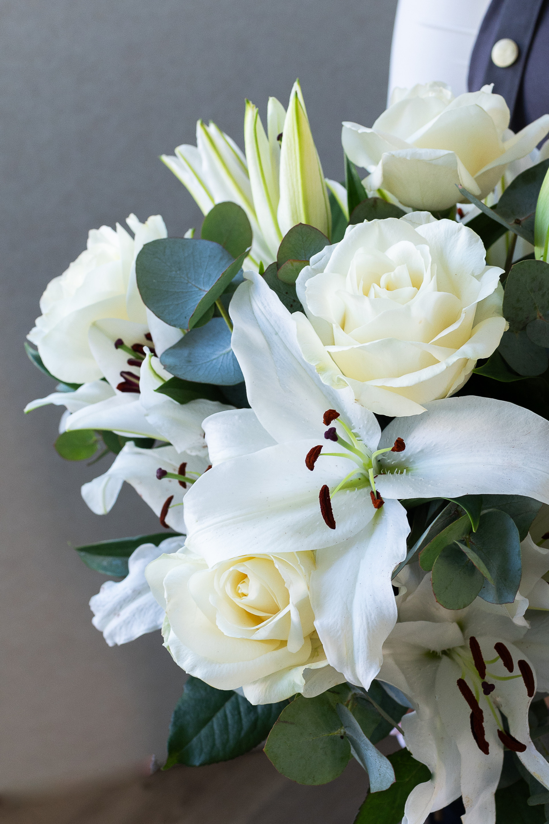 Close-up of white lilies, ivory roses, and eucalyptus.