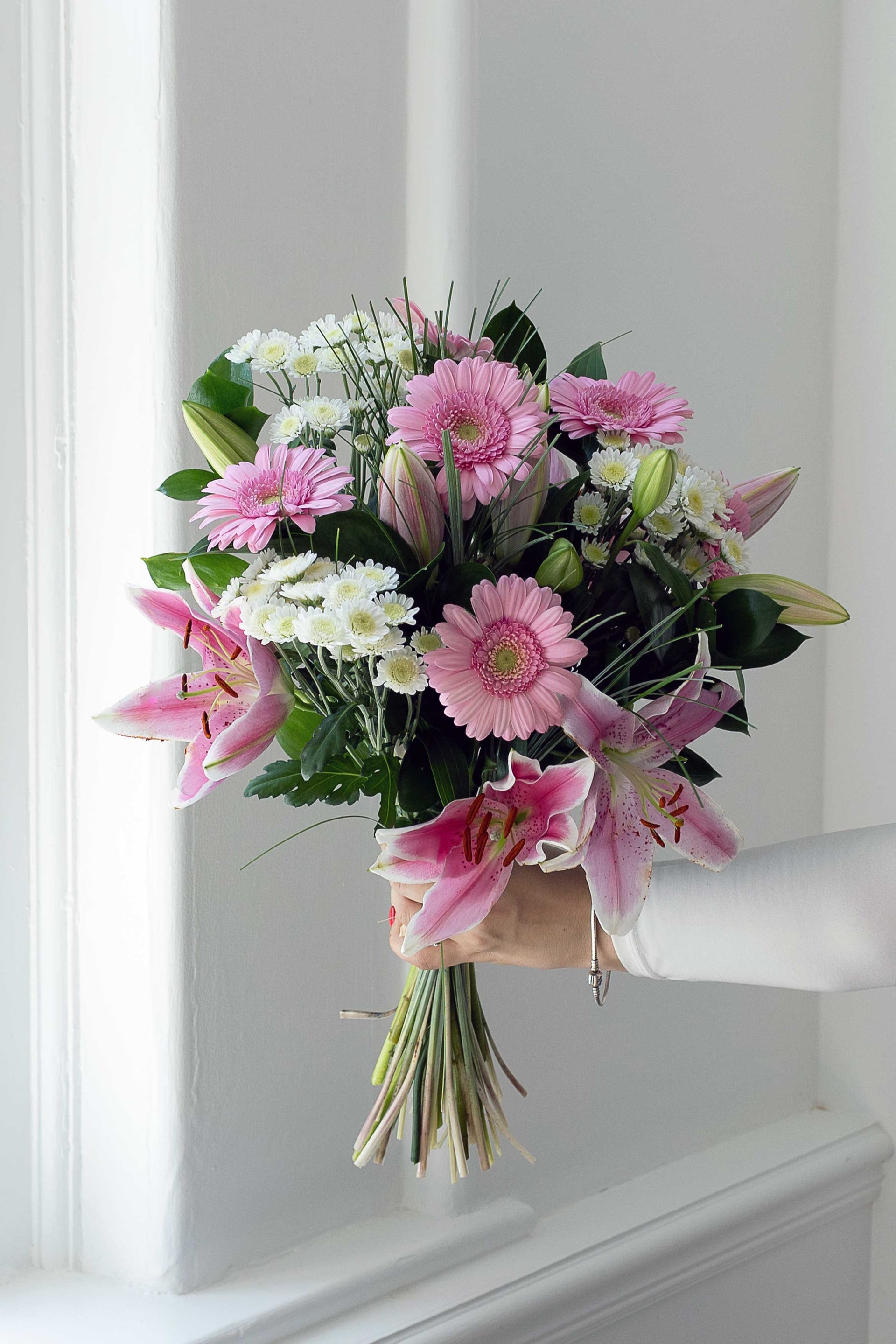 Pastel bouquet of pink lilies, gerberas and white flowers.