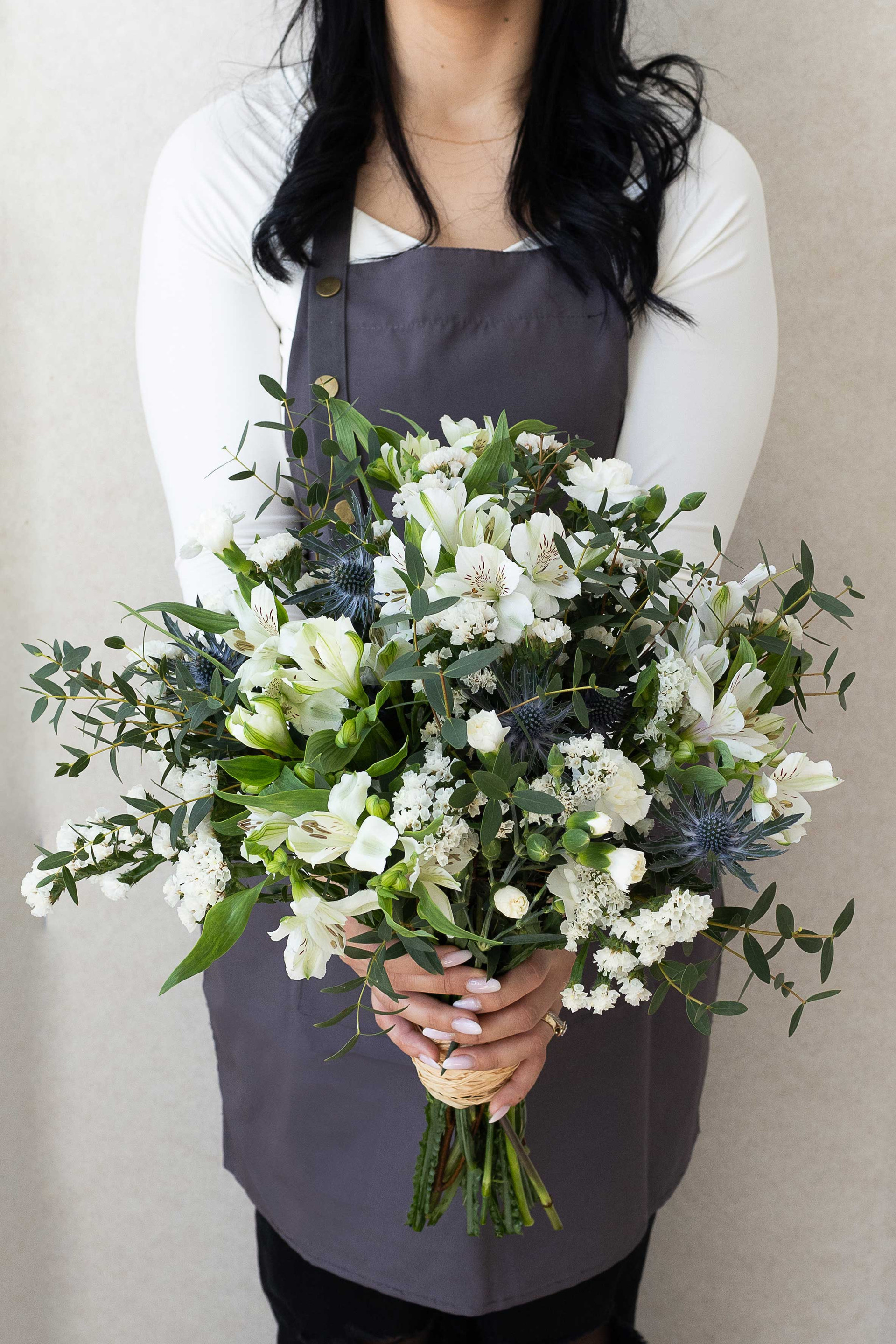 Garden-style white bouquet with eucalyptus and eryngium thistles.