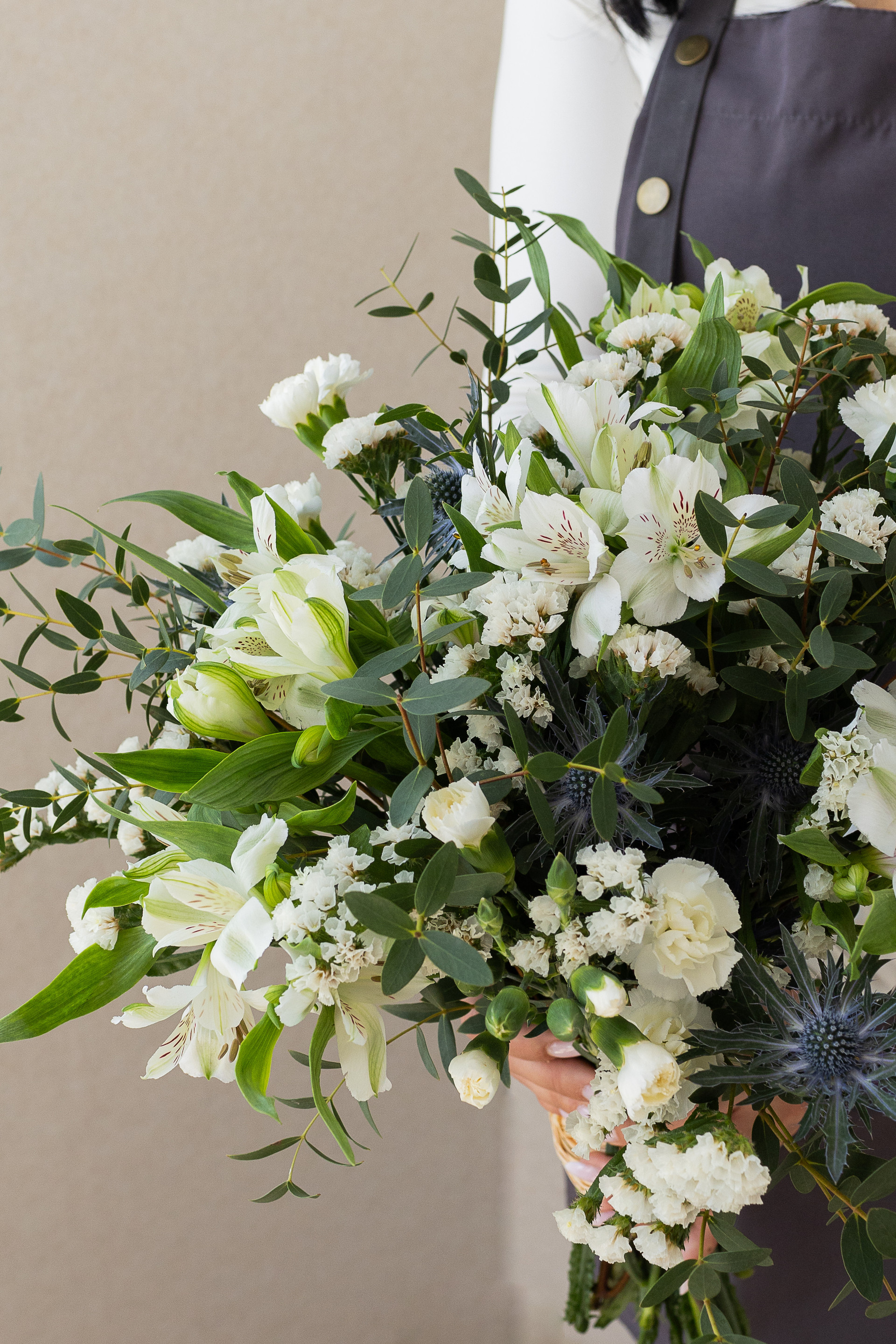 Close-up of white flowers, eucalyptus, and blue thistles.