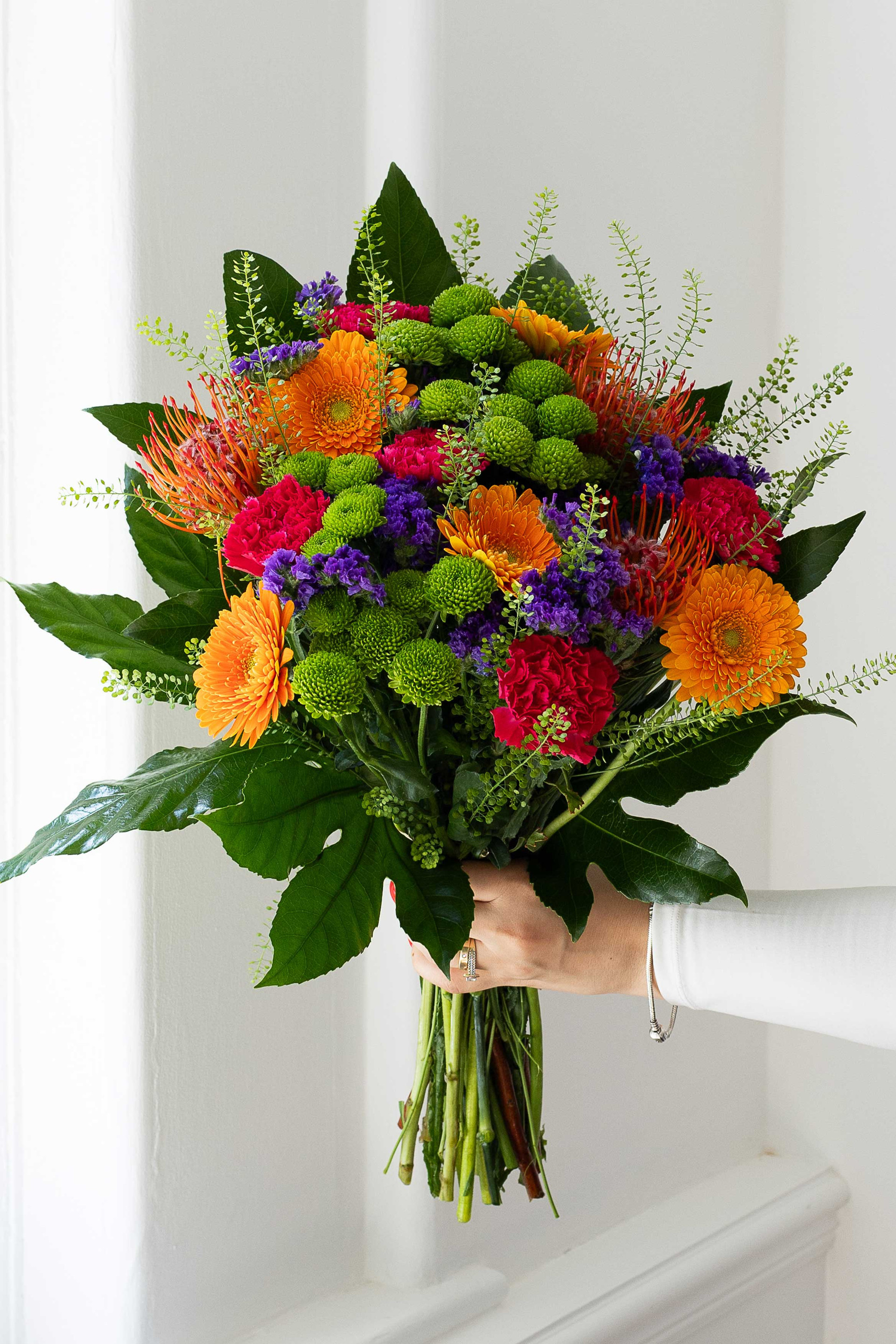 Vibrant bouquet of orange, green, pink, and purple flowers.