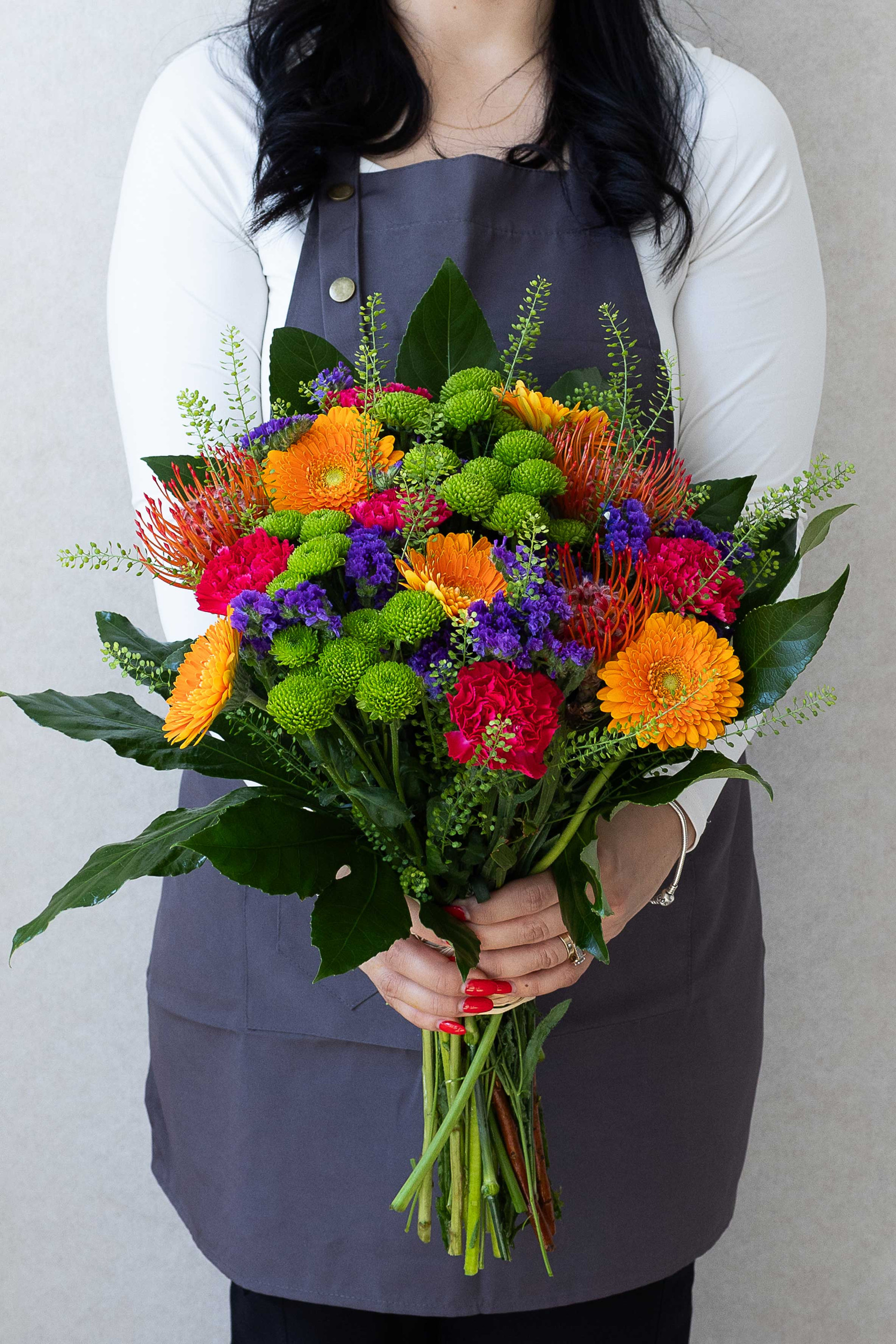 Colourful bouquet with orange gerberas, pincushion protea, green chrysanthemums, and pink carnations.