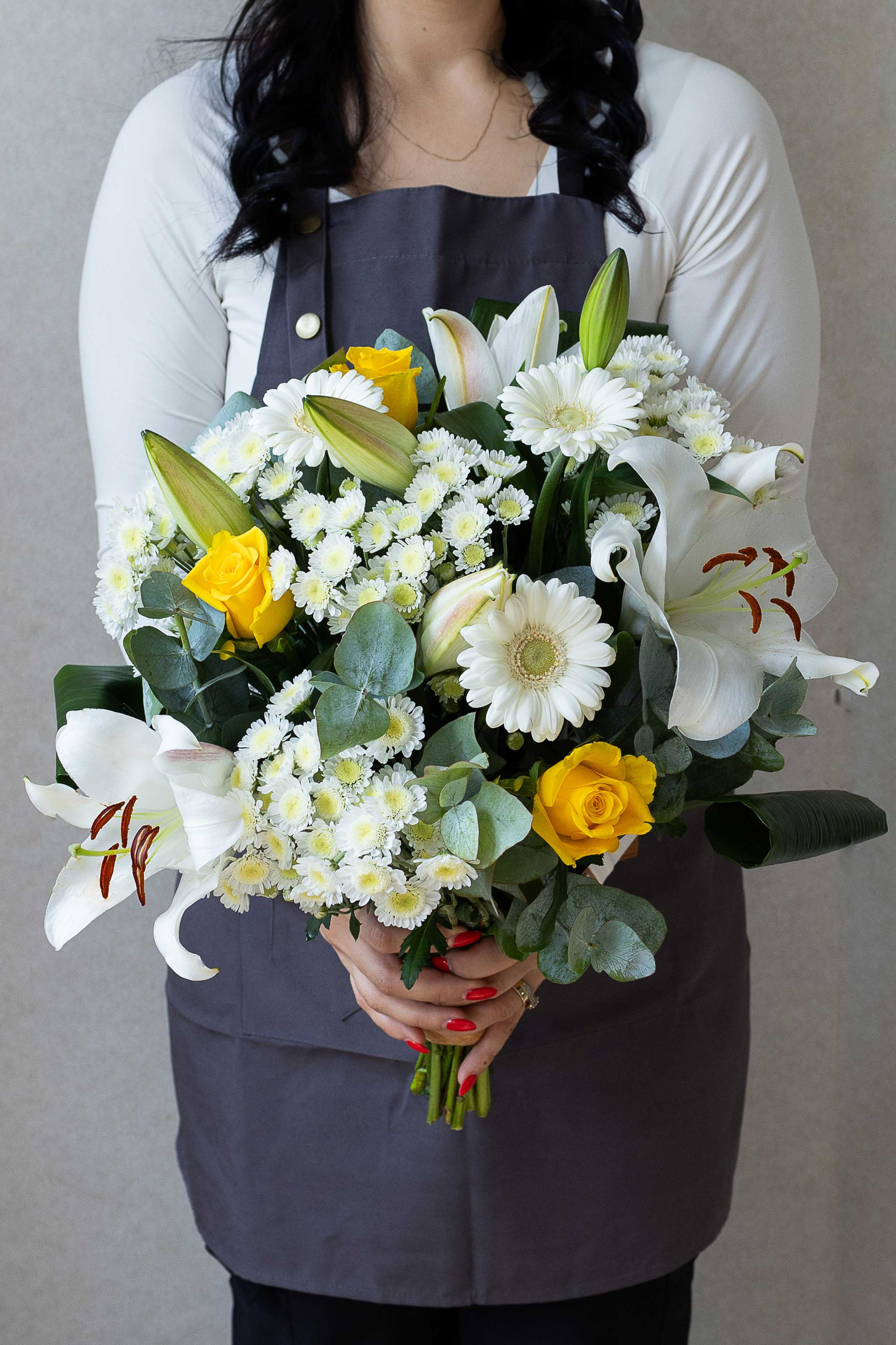 Florist holding a white and yellow mixed flower bouquet.