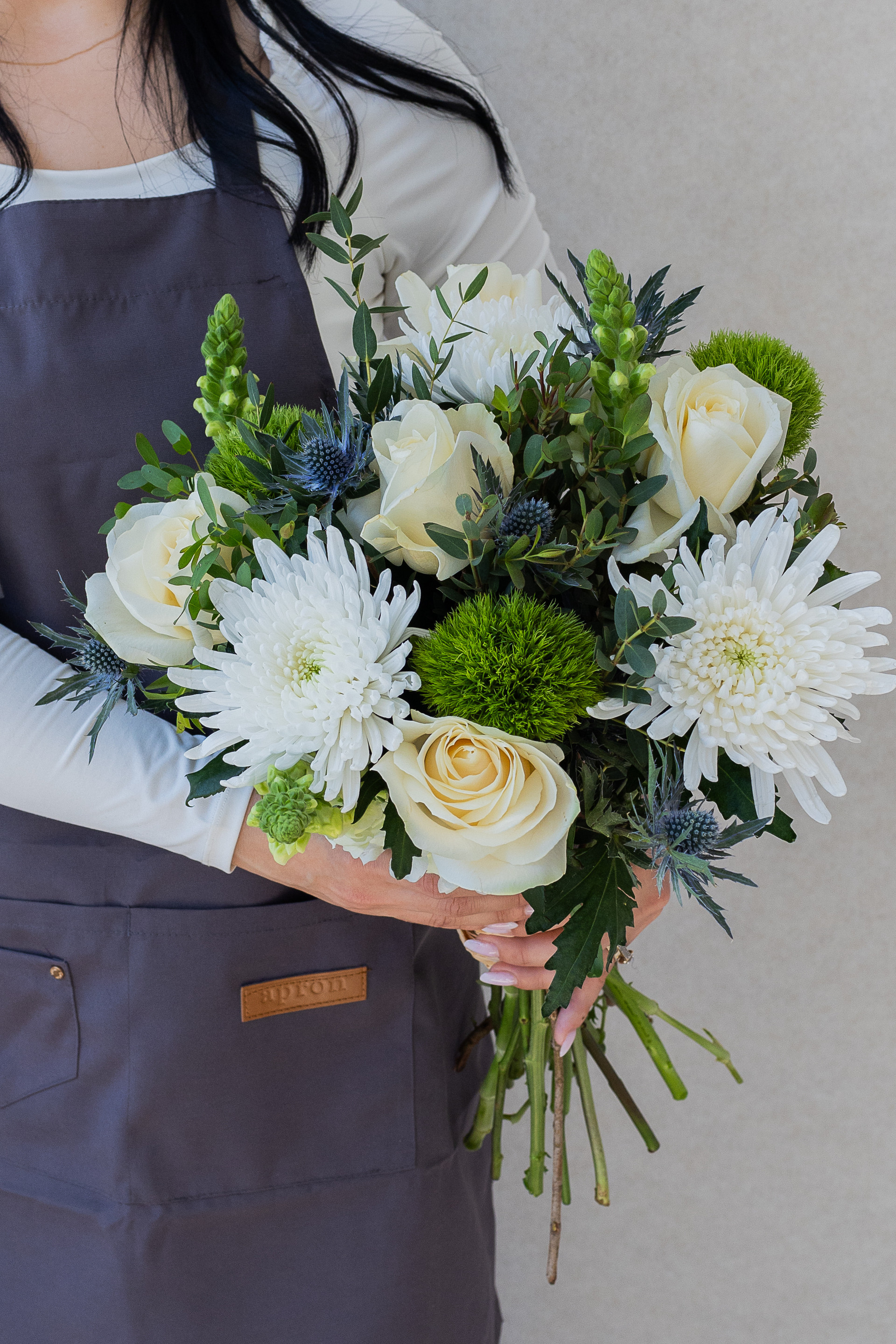 Florist holding an ivory, white, and green mixed flower bouquet.