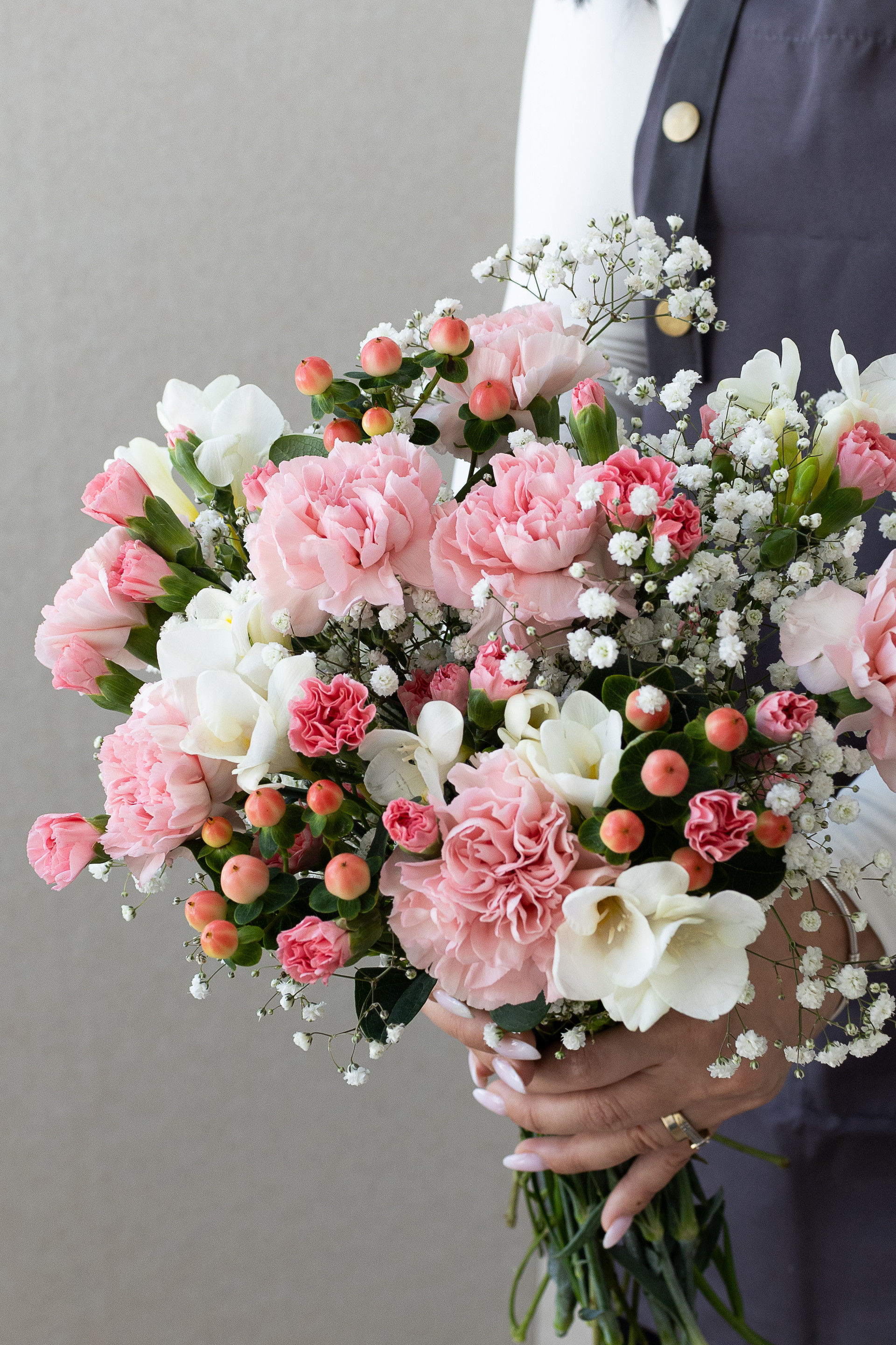 Close-up of pink carnations, white freesia, hypericum berries, and gypsophila.