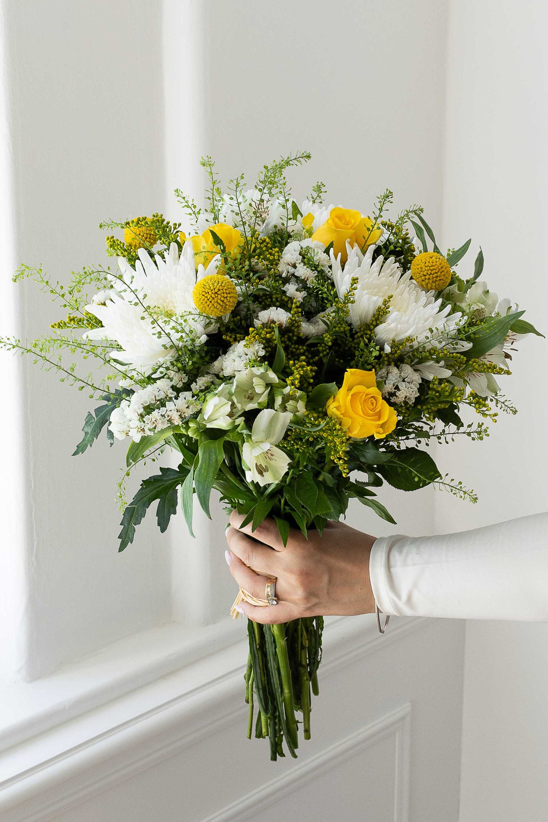 Yellow rose bouquet with white flowers and greenery.
