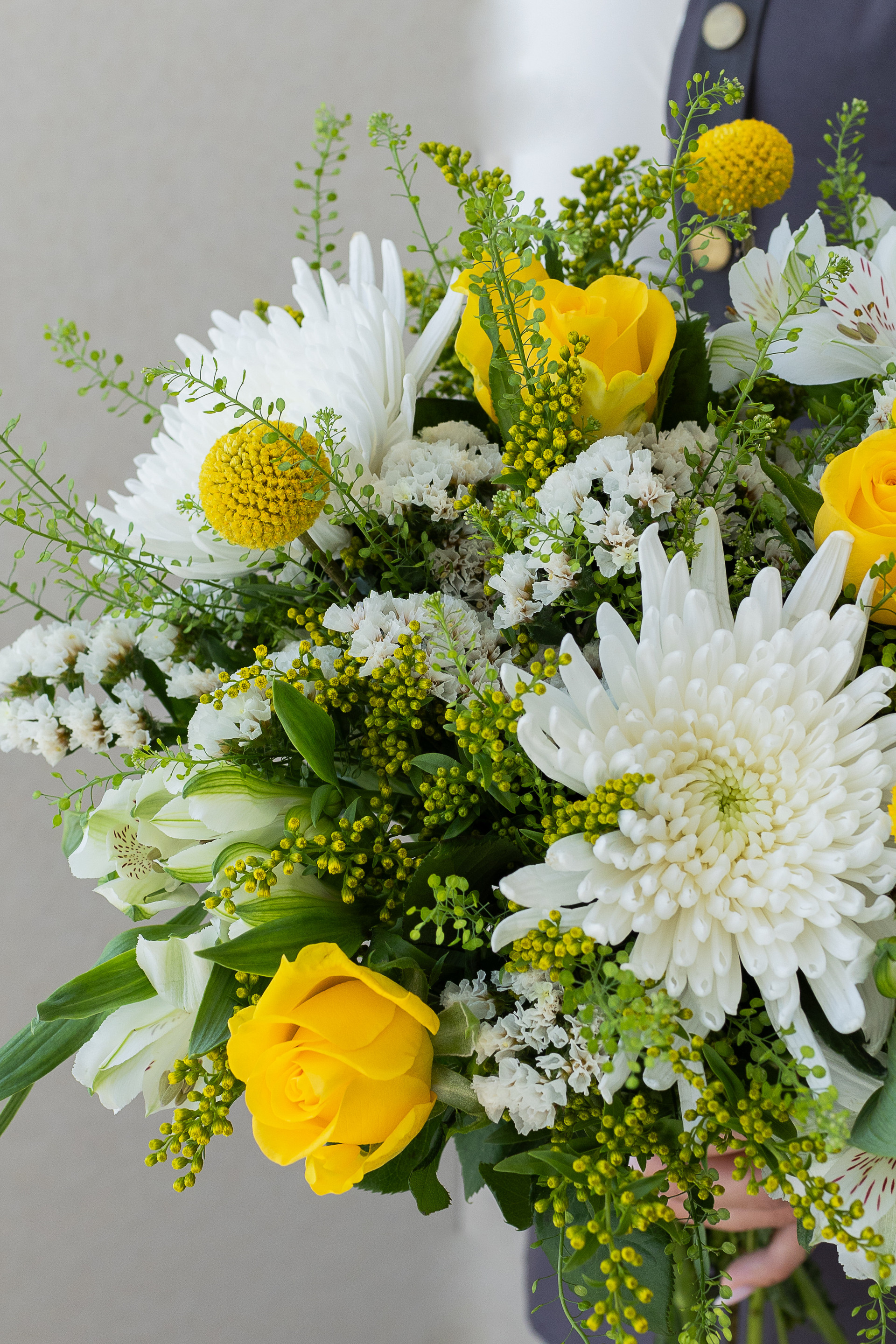 Close-up of yellow roses, white chrysanthemums, and craspedia.