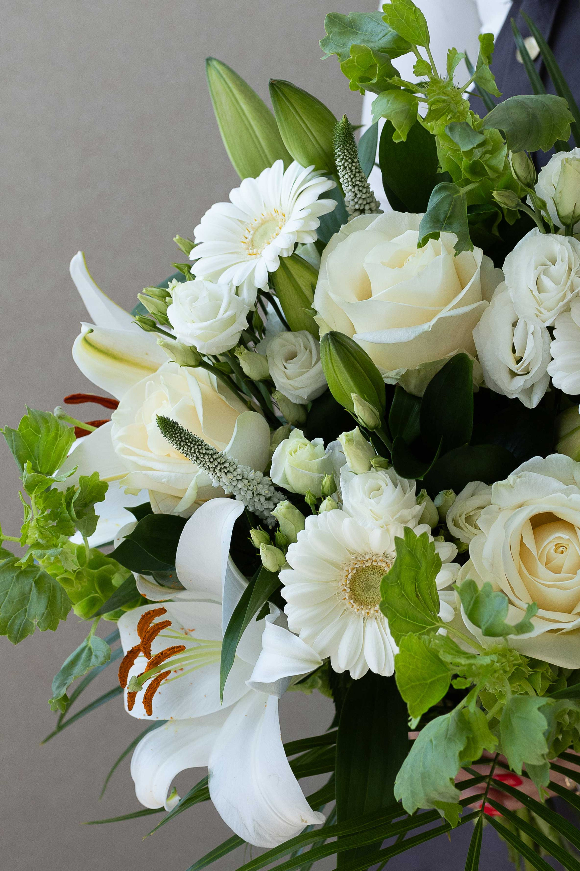 Close-up of white lilies, ivory roses, germini daisies, and lisianthus.