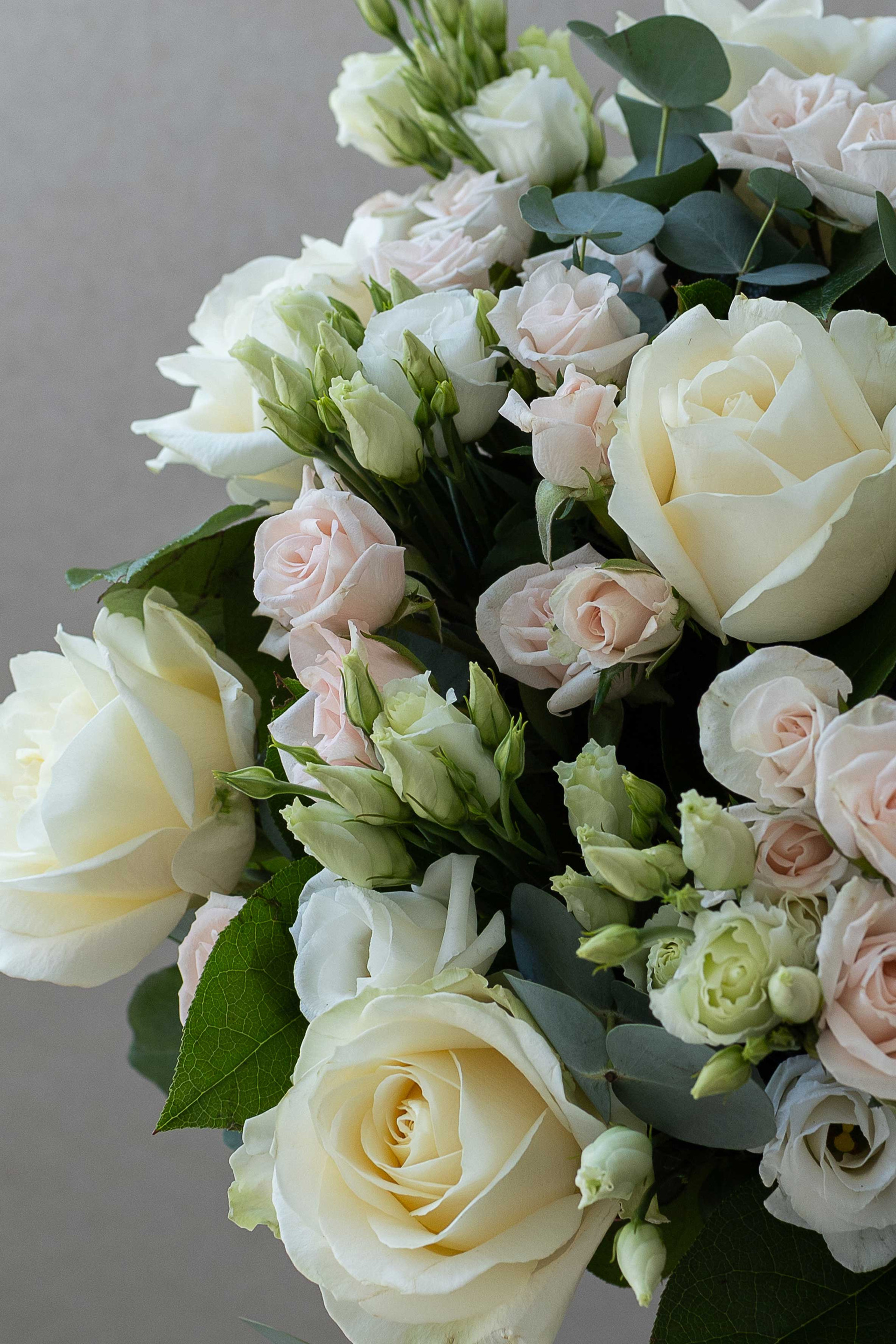 Close-up of ivory roses, blush spray roses, and lisianthus.