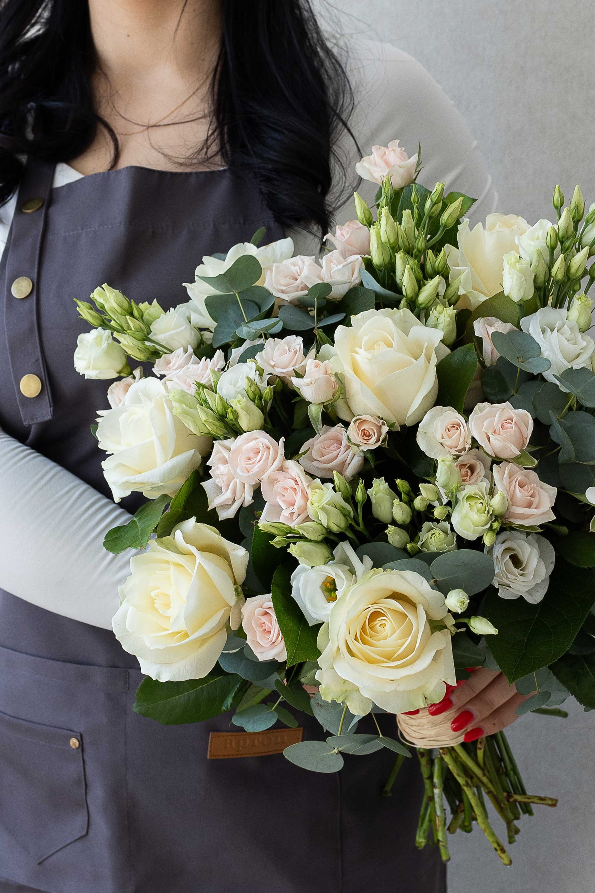Florist holding an ivory and blush rose bouquet.