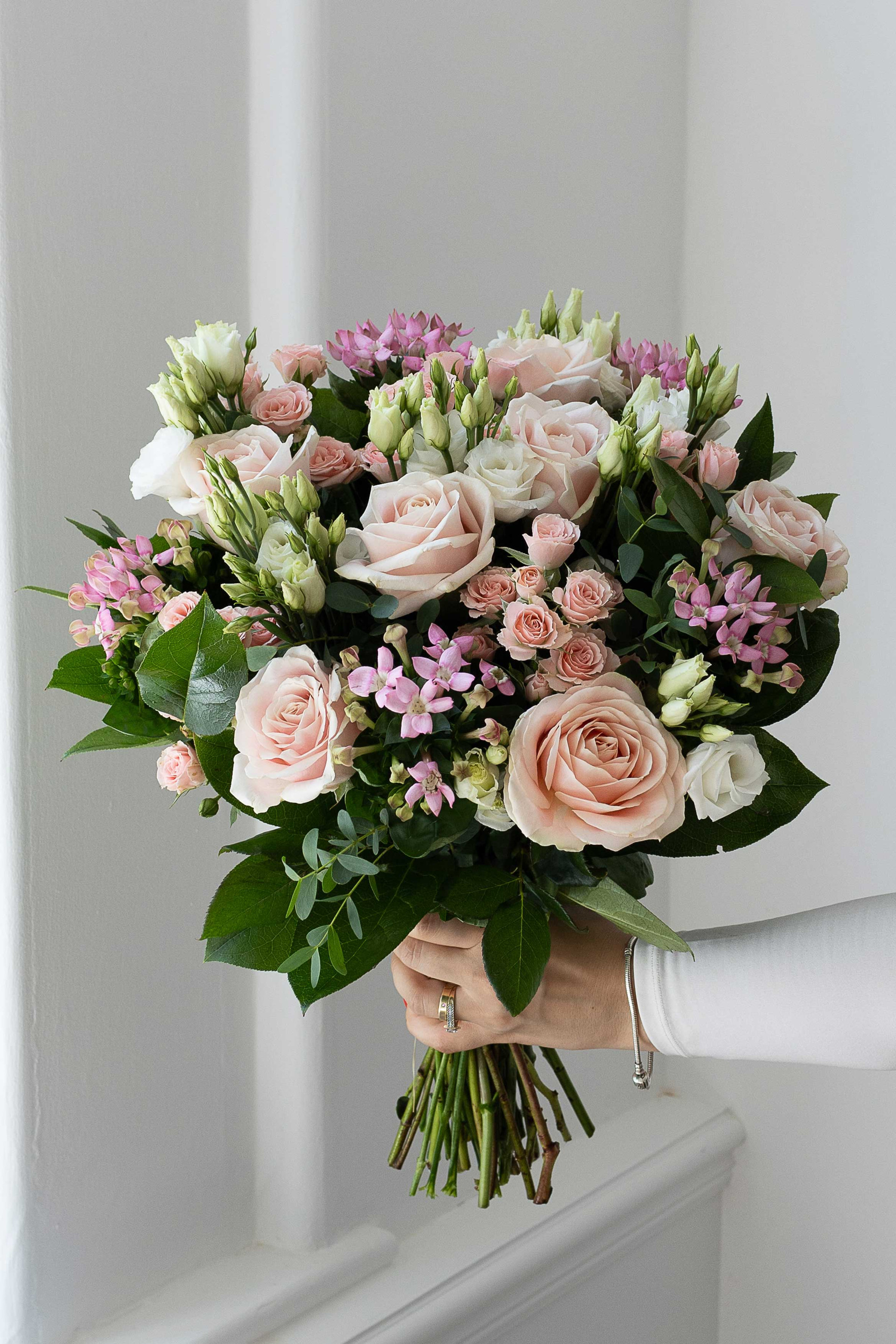 Pastel pink and white bouquet with roses and greenery.