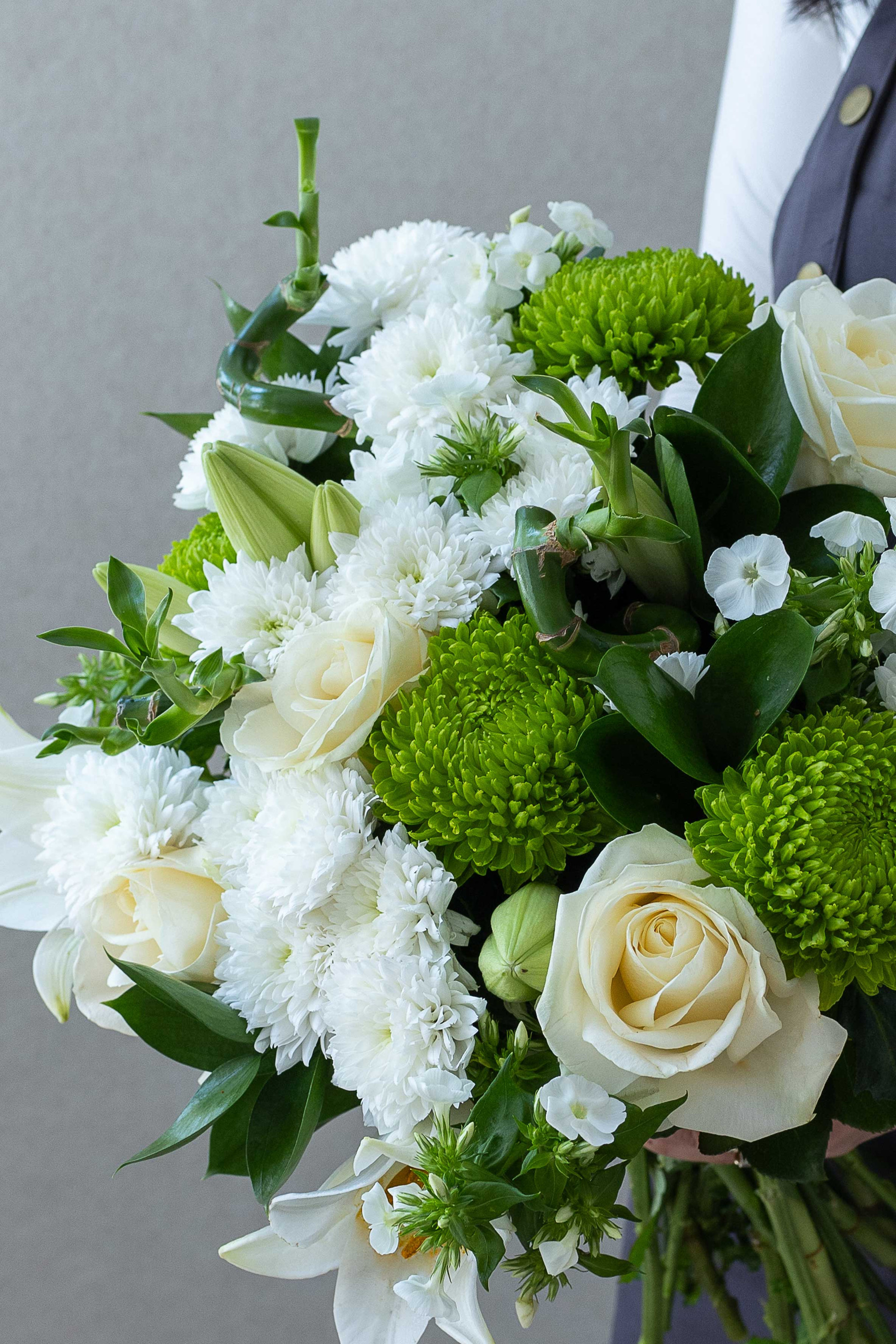 Close-up of white roses, lilies, chrysanthemums, and green button mums.