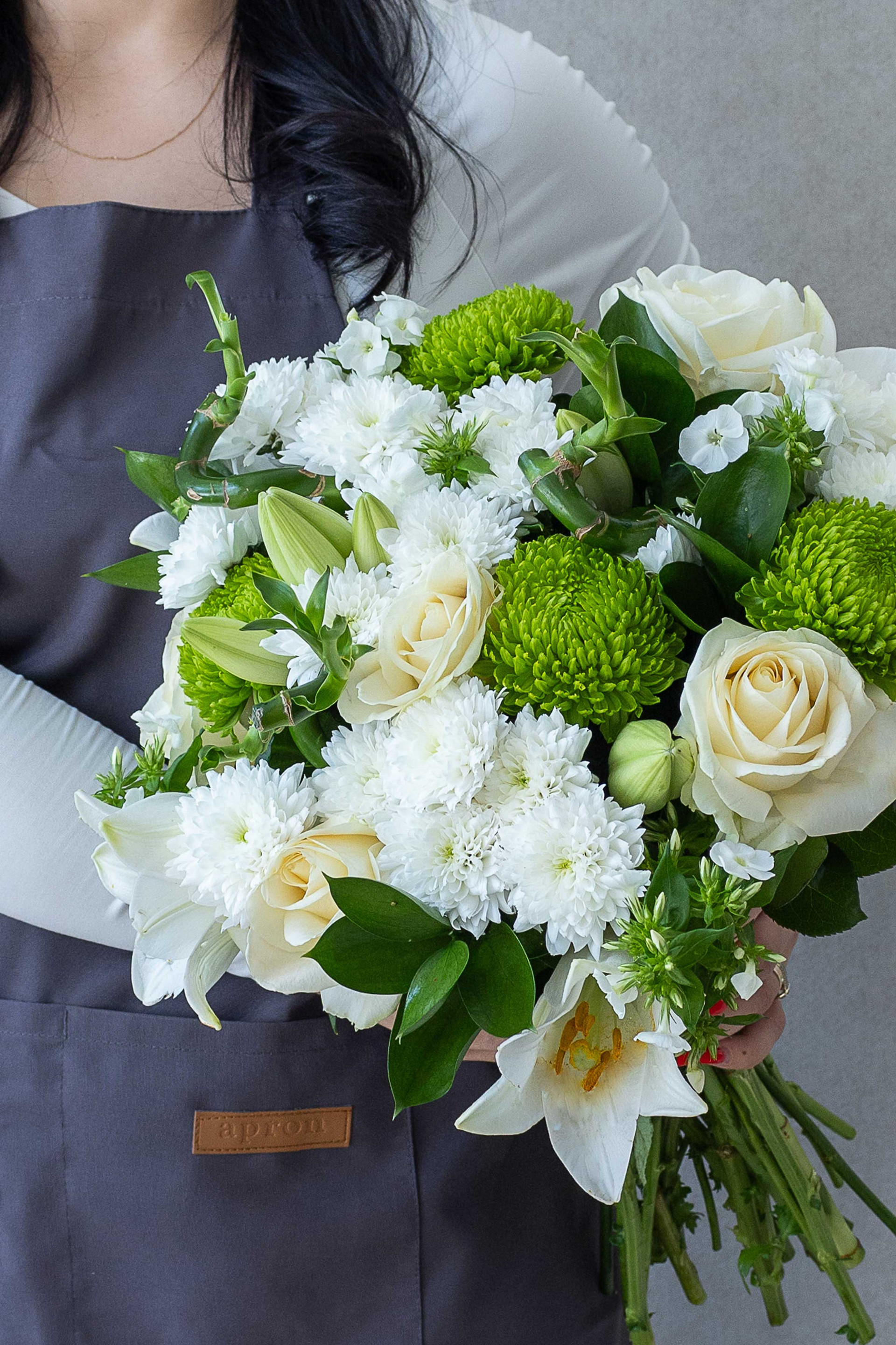 White and green bouquet with roses, lilies, bamboo, and chrysanthemums.