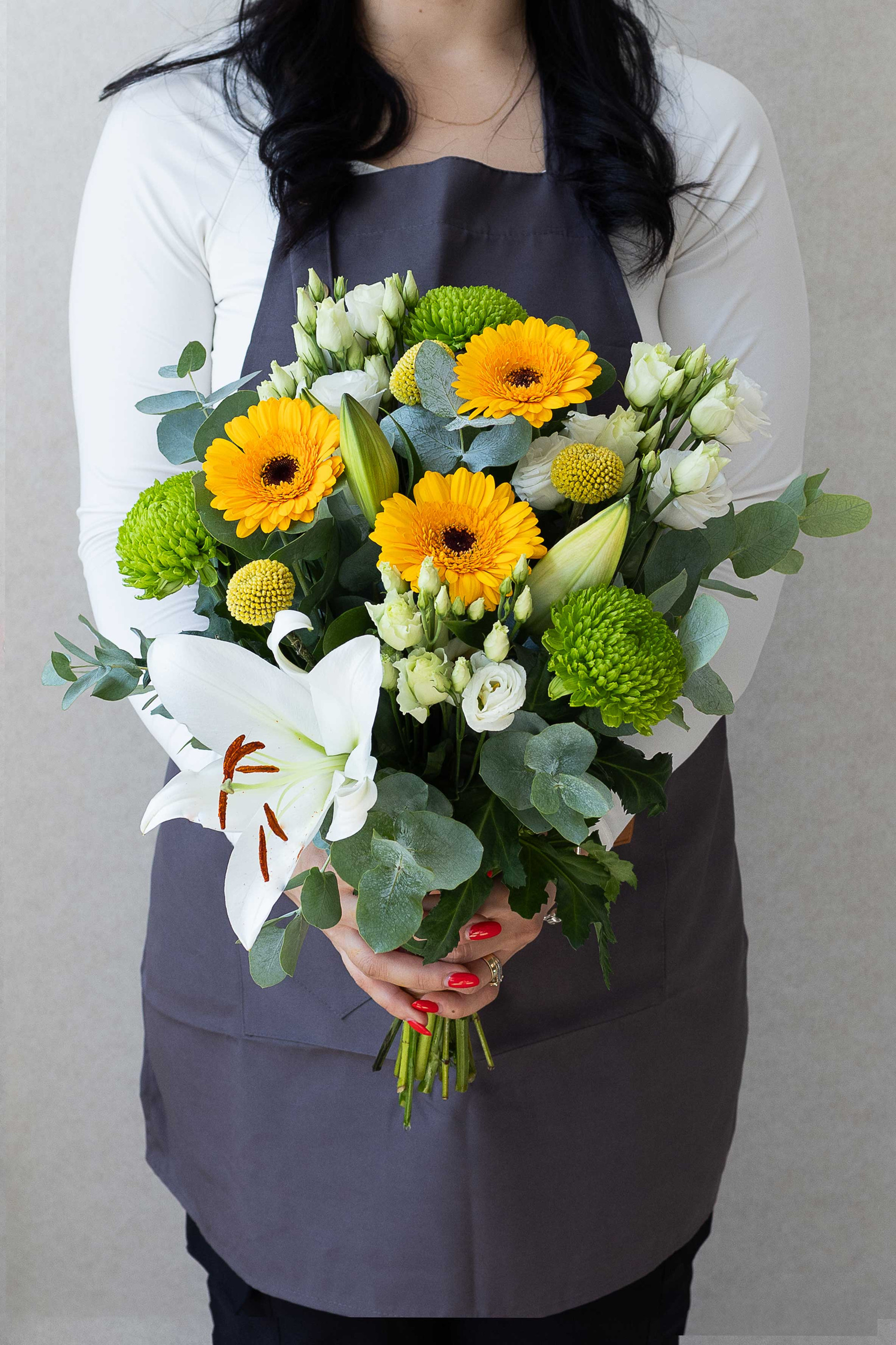 Bouquet of yellow gerberas, white lily, lisianthus, green chrysanthemums, and eucalyptus.