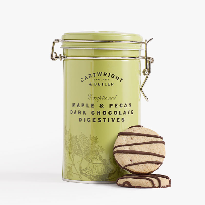 Pale green clip-top tin of Cartwright & Butler Maple & Pecan Dark Chocolate Digestives with chocolate-drizzled biscuits displayed in front.