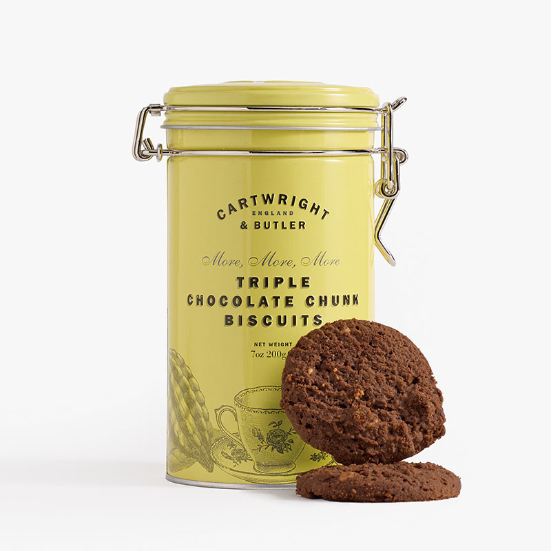 Pale yellow clip-top tin of Cartwright & Butler Triple Chocolate Chunk Biscuits with two dark chocolate biscuits displayed in front.