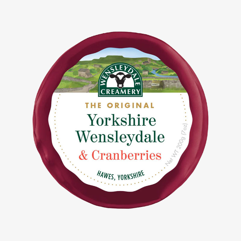 Round red wax-wrapped Wensleydale Creamery Yorkshire Wensleydale & Cranberries cheese with a countryside-themed label.