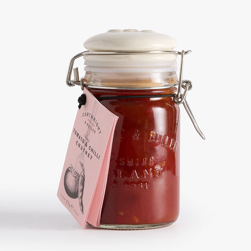 Clip-top glass jar of Cartwright & Butler Tomato & Chilli Chutney with a pale pink hanging label and red chutney visible inside.